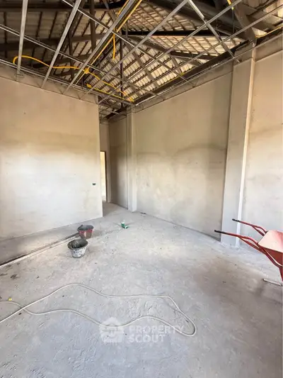Spacious unfinished room with exposed ceiling and construction materials, ideal for customization.