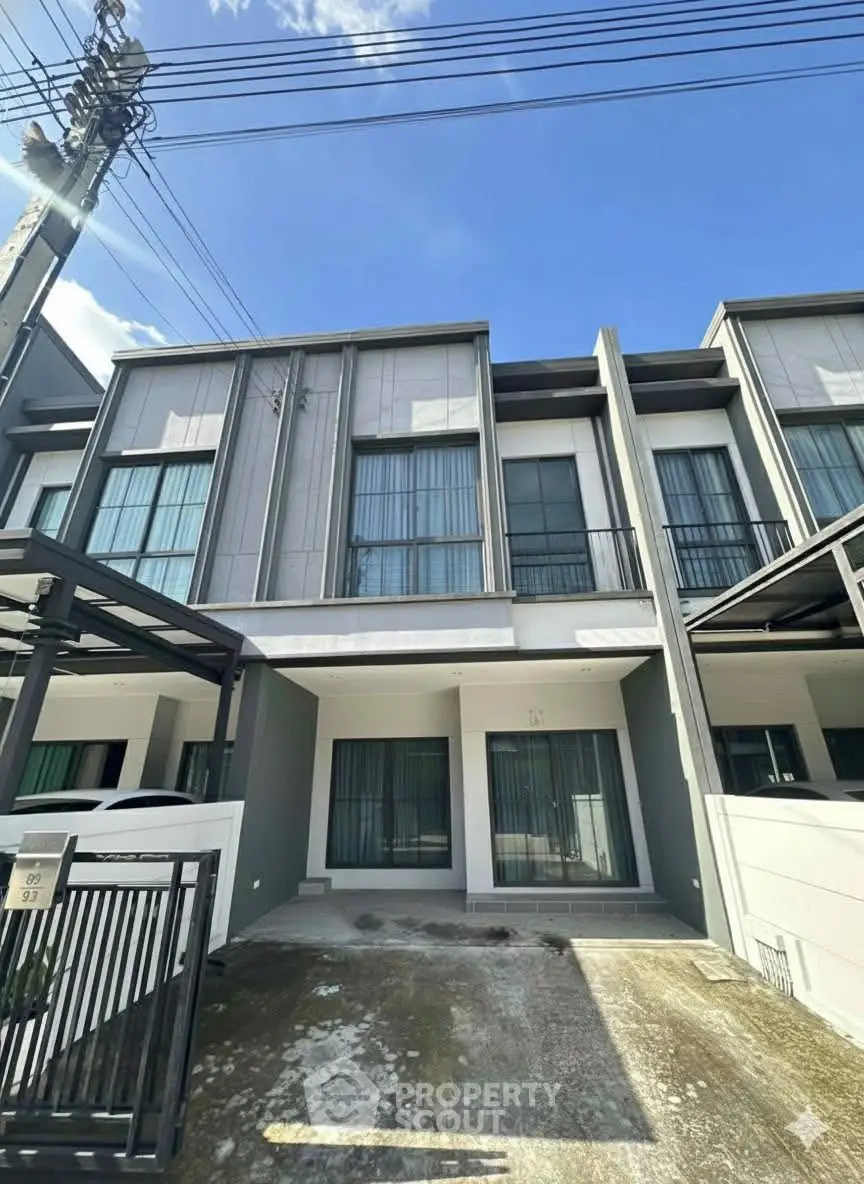 Modern townhouse exterior with sleek design and large windows under a clear blue sky.