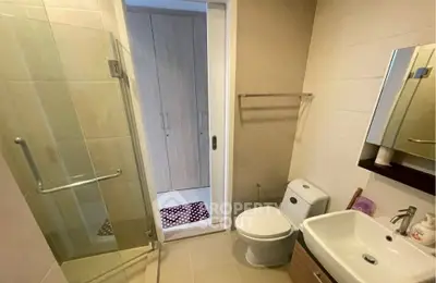 Modern bathroom with glass shower, sleek sink, and toilet in contemporary apartment.