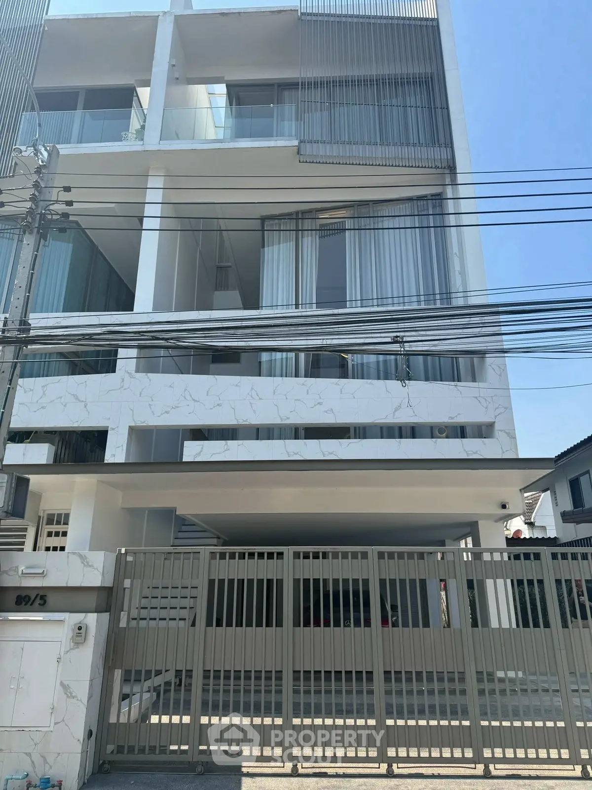 Modern multi-story building with sleek design and gated entrance in urban setting.