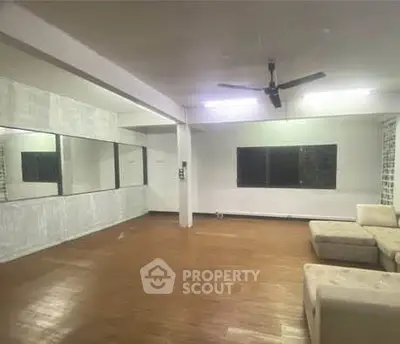 Spacious living room with wooden flooring and large mirrors, ideal for modern living.