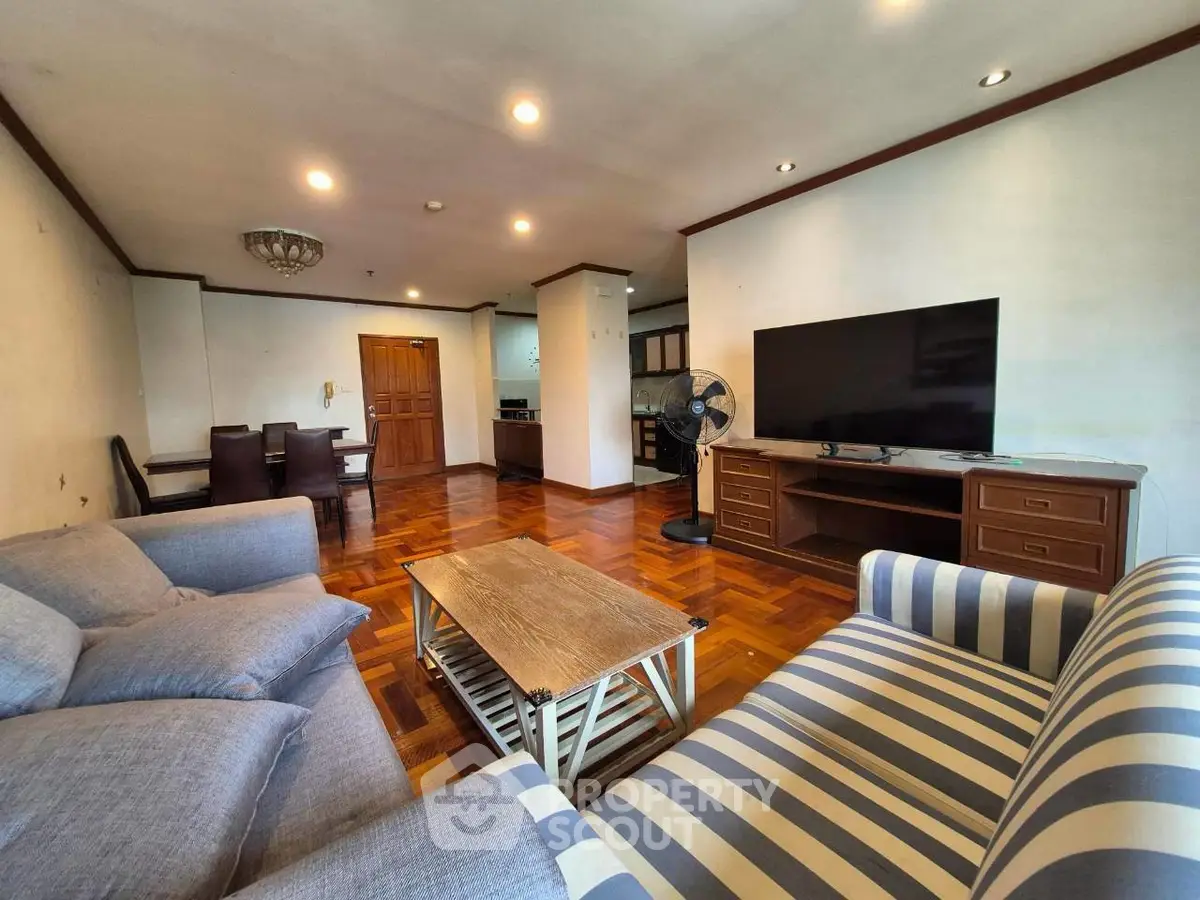 Spacious living room with stylish furniture and large TV, perfect for relaxation and entertainment.