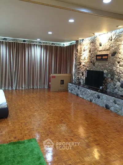 Spacious living room with stone accent wall and parquet flooring