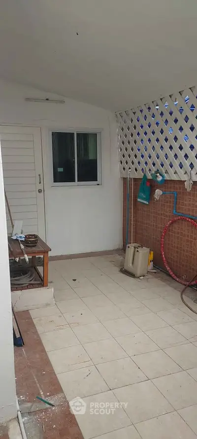 Cozy enclosed balcony with tiled flooring and lattice wall, perfect for relaxation.