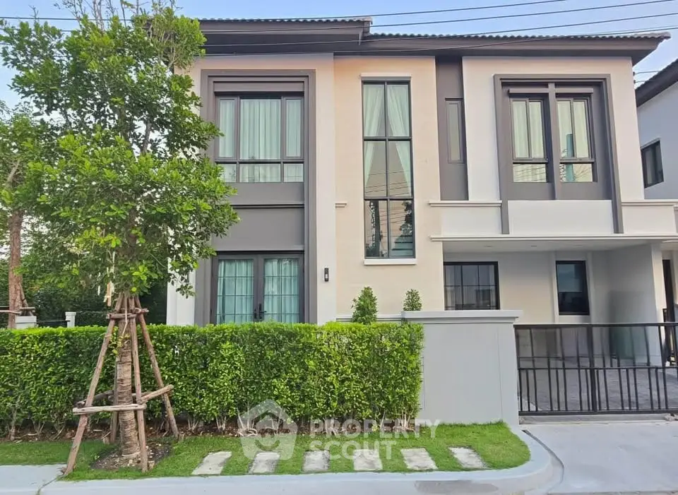 Modern two-story house with large windows and manicured garden