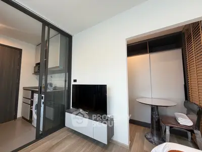 Modern apartment interior with compact kitchen and cozy living area featuring a sleek TV unit.