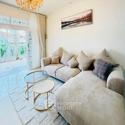 Elegant living room with plush sofas and chic coffee tables, featuring large windows and a serene outdoor view.