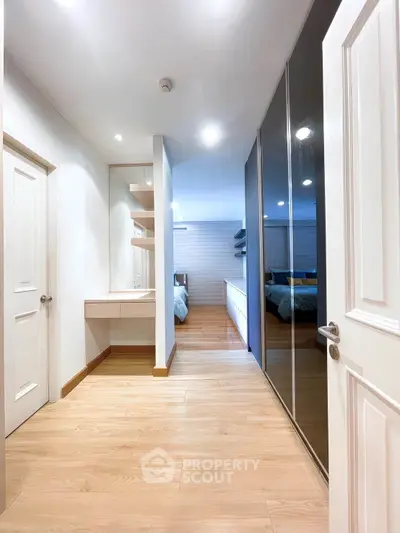 Spacious modern bedroom with wooden flooring and sleek mirrored closet doors.