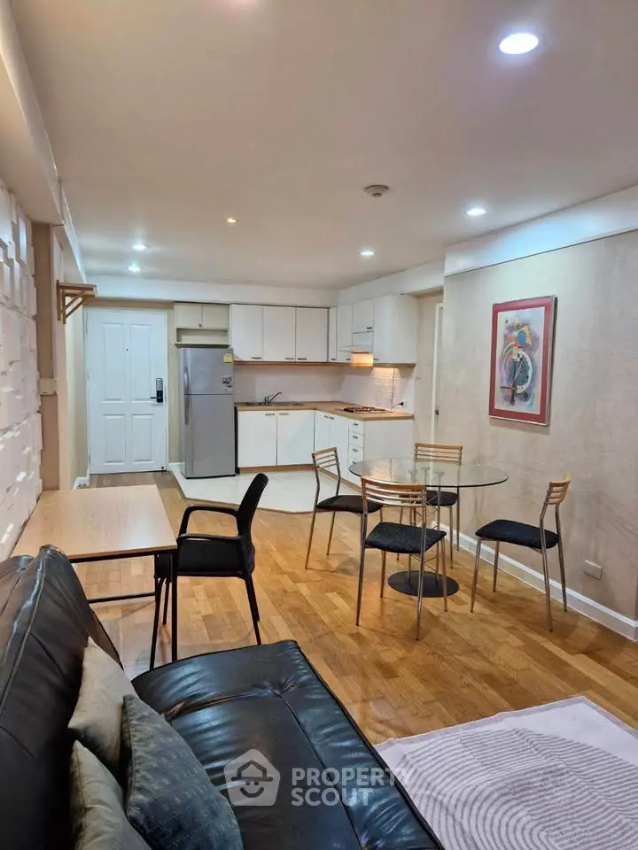 Modern open-plan living room with sleek kitchen and dining area, featuring hardwood floors and contemporary decor.