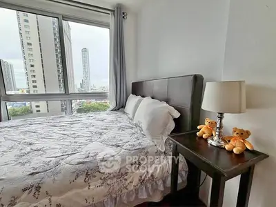 Cozy bedroom with city view, featuring a plush bed and bedside table with lamp and teddy bears.