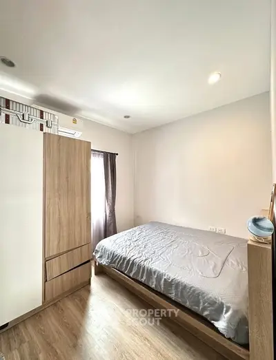 Cozy bedroom with natural light, wooden flooring, and modern furnishings for a comfortable living experience.