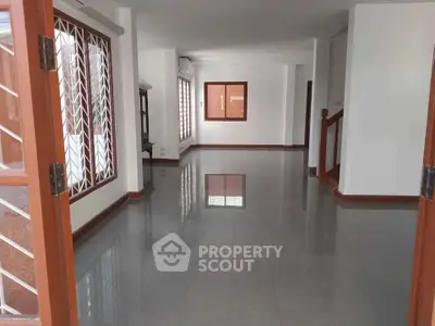 Spacious open-plan living area with large windows and glossy tiled floors.