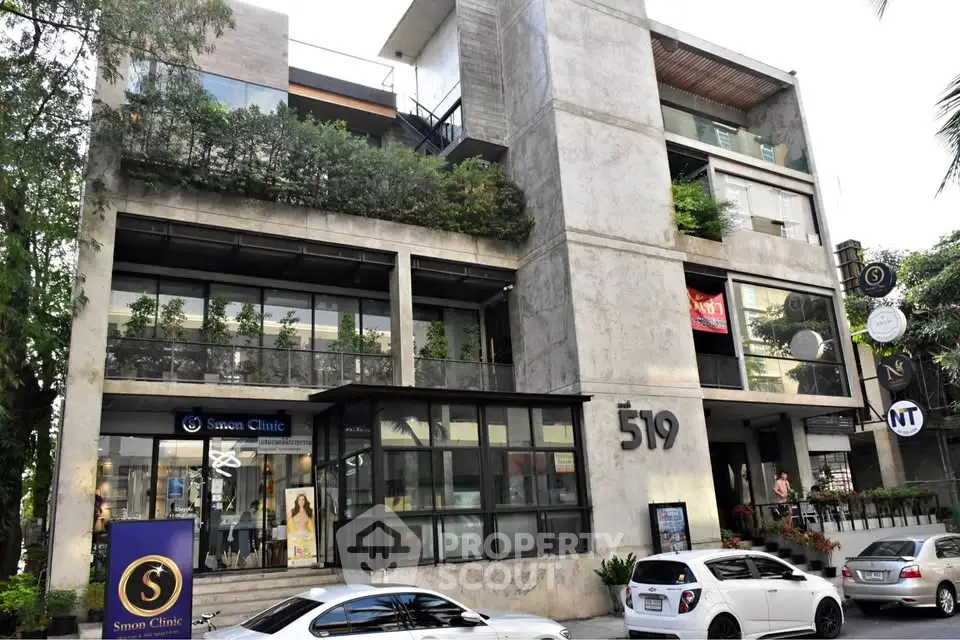 Modern commercial building with large windows and greenery in urban setting