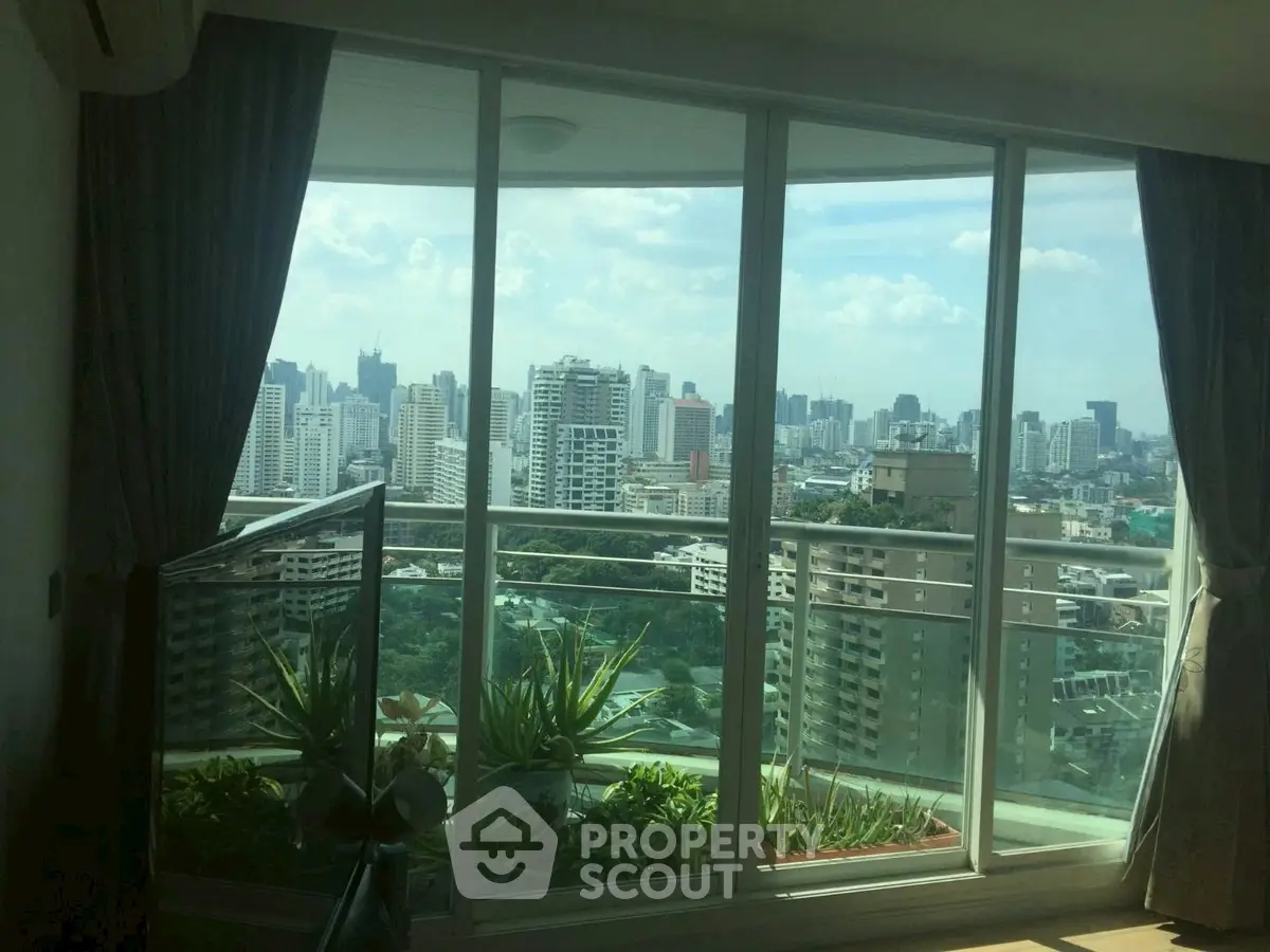 Stunning cityscape view from modern apartment balcony with lush greenery.