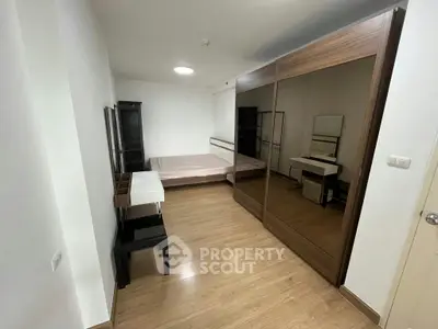 Spacious bedroom with modern mirrored wardrobe and wooden flooring
