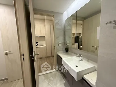Modern bathroom with sleek sink and mirror, adjacent to a stylish kitchen.