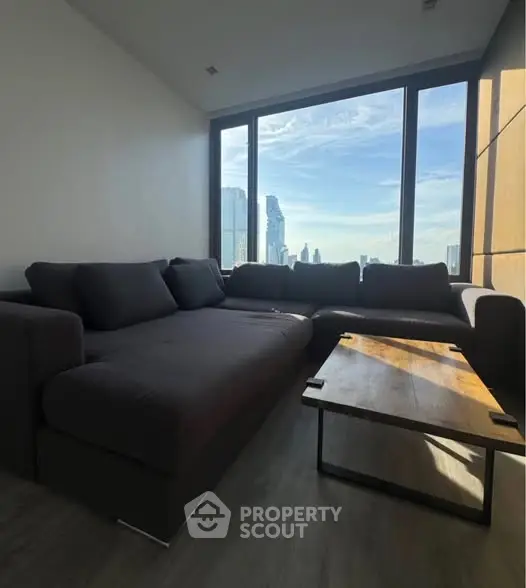 Modern living room with large windows offering stunning city views and stylish furniture.