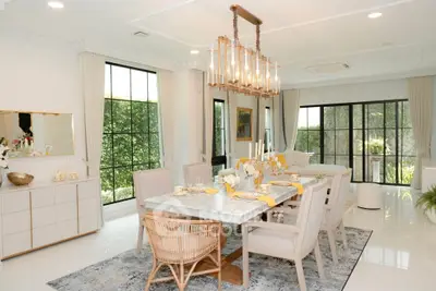 Luxurious dining room with elegant chandelier and large windows offering garden views.