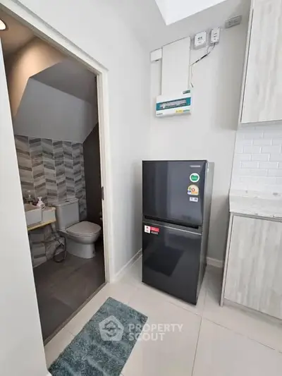 Modern kitchen with sleek fridge and adjacent bathroom in stylish apartment