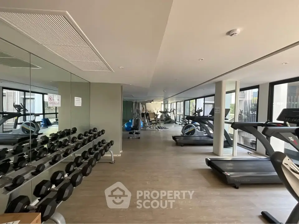 Spacious modern gym with state-of-the-art equipment and large windows for natural light.