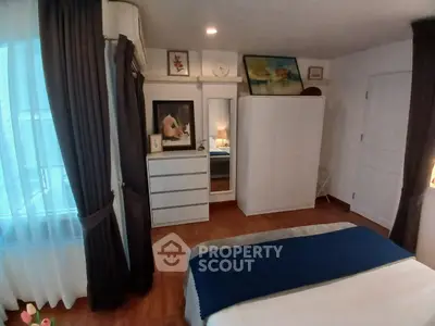 Cozy bedroom with elegant decor and ample natural light, featuring a stylish wardrobe and tasteful artwork.