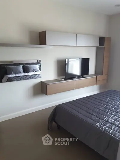 Modern bedroom with sleek wall-mounted TV and stylish storage units.