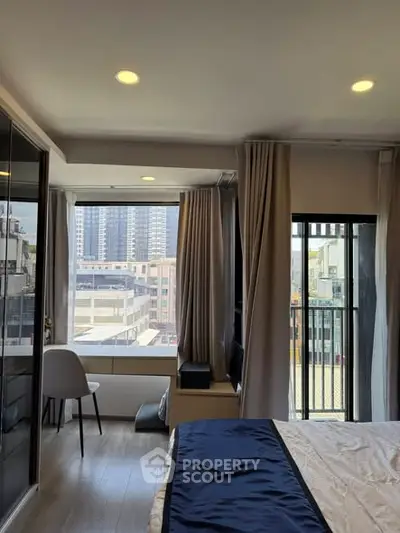 Modern bedroom with large windows and city view, featuring elegant decor and natural light.