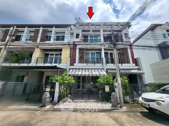 Modern townhouse with three floors and gated entrance in a residential area.