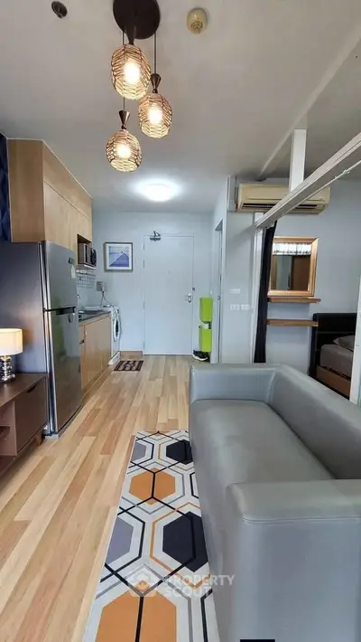 Modern living room with open kitchen, stylish lighting, and cozy decor in a contemporary apartment.