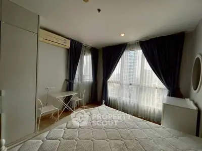 Cozy bedroom with large windows and city view, featuring modern furniture and elegant curtains.