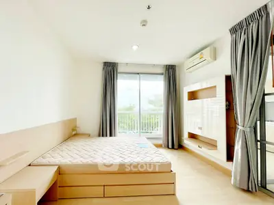 Spacious bedroom with balcony view, modern furnishings, and natural light.