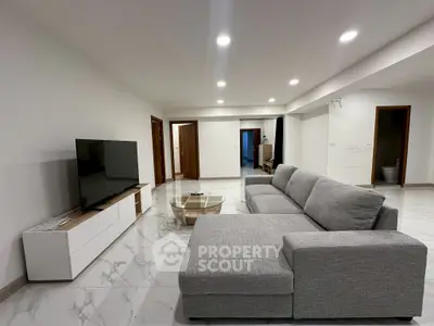 Spacious modern living room with sleek gray sectional sofa and large flat-screen TV.