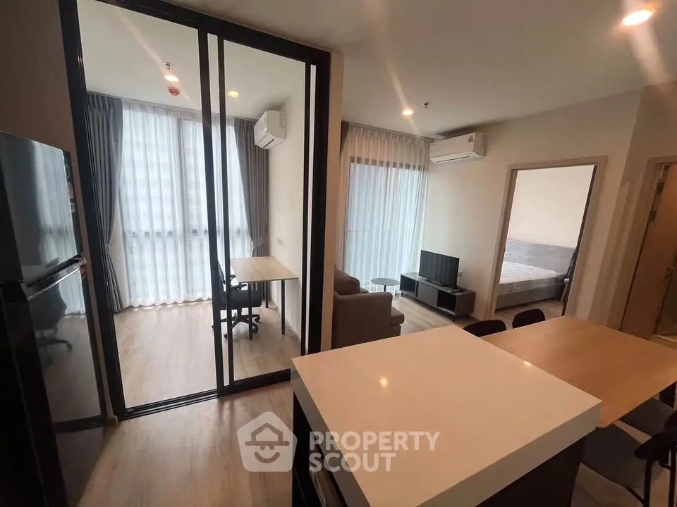 Modern open-plan living room with study area and bedroom in a stylish apartment.