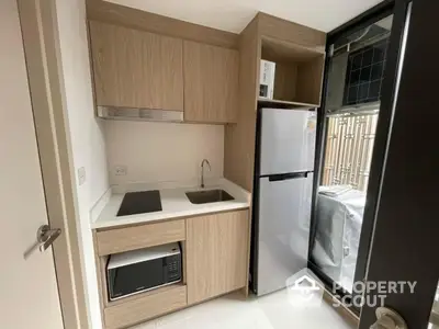 Modern compact kitchen with sleek cabinetry and appliances in a stylish apartment.