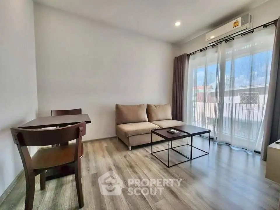 Modern living room with cozy sofa, wooden flooring, and large windows for natural light.