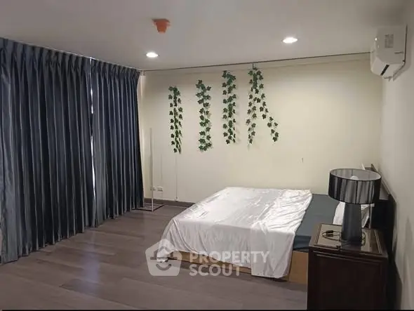 Spacious bedroom with modern decor and large windows for natural light.