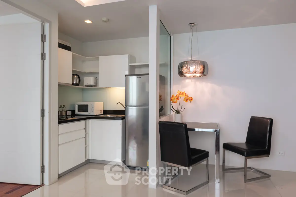 Modern kitchen with sleek appliances and cozy dining area in a stylish apartment.