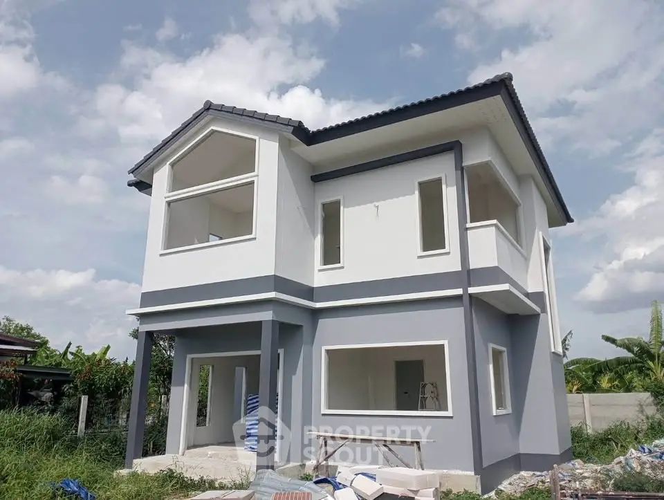 Modern two-story house with sleek design and large windows, set against a clear blue sky.