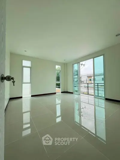 Spacious empty room with large windows and glossy tiled floor, offering abundant natural light and modern design.