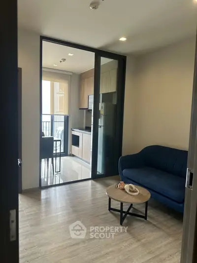 Modern living room with blue sofa and open kitchen layout, perfect for cozy urban living.
