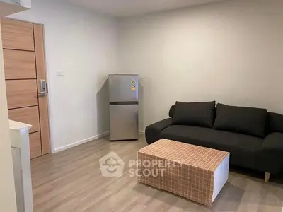 Modern living room with sleek black sofa and compact fridge, perfect for urban living.