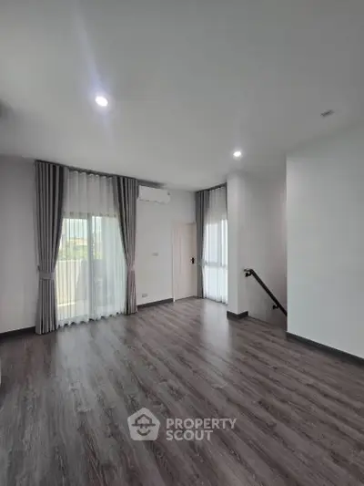 Spacious empty room with elegant flooring and large windows, perfect for customization.