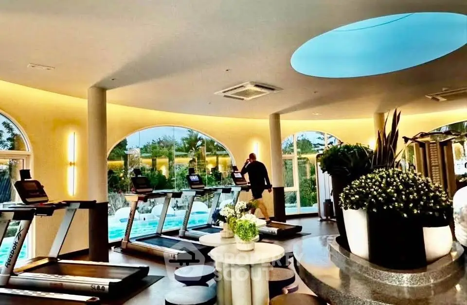 Luxurious gym with modern equipment and pool view in upscale real estate property.