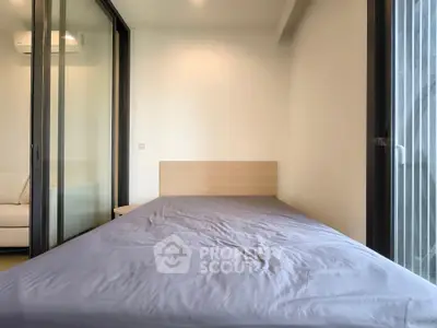 Modern bedroom with large windows and minimalist design, featuring a comfortable bed and natural light.