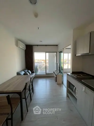 Modern apartment with open layout, featuring a cozy living area and kitchen, overlooking a scenic view.