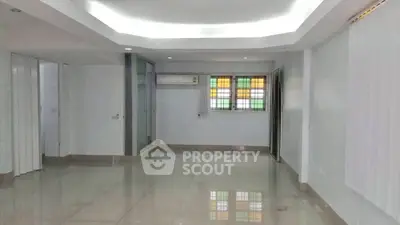 Spacious empty room with tiled flooring and colorful window panes, ideal for customization.