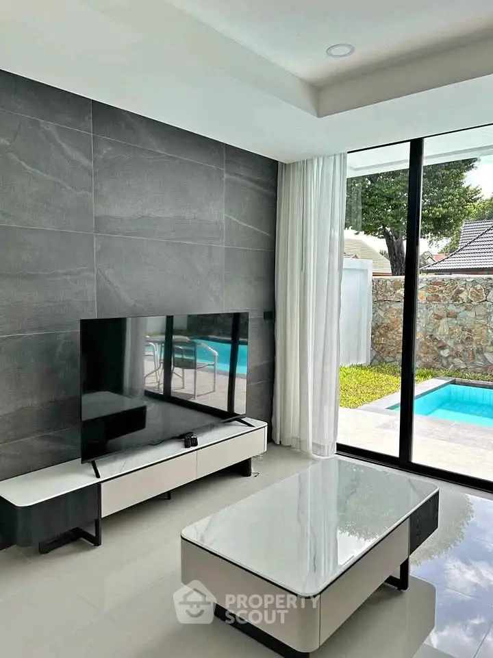 Modern living room with pool view, sleek furniture, and large windows for natural light.