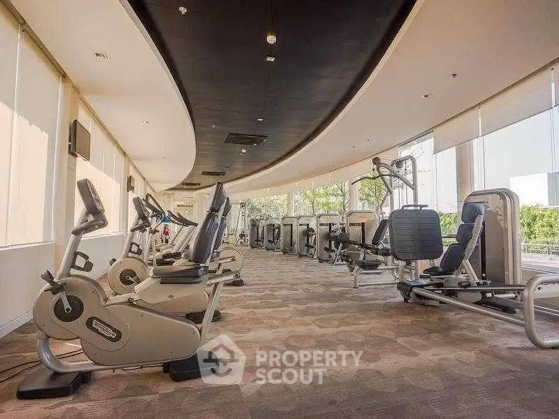Spacious modern gym with state-of-the-art fitness equipment and large windows for natural light.