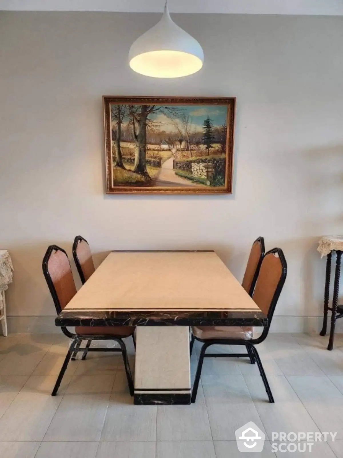 Elegant dining area with modern table and chairs, highlighted by a beautiful landscape painting.