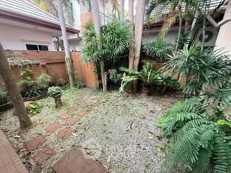 Charming garden oasis with lush greenery and stone pathway in a serene residential setting.